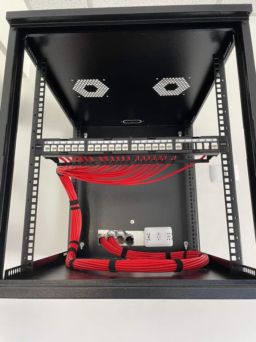 Rack de parede com patch panel Cat6A e cabos vermelhos organizados